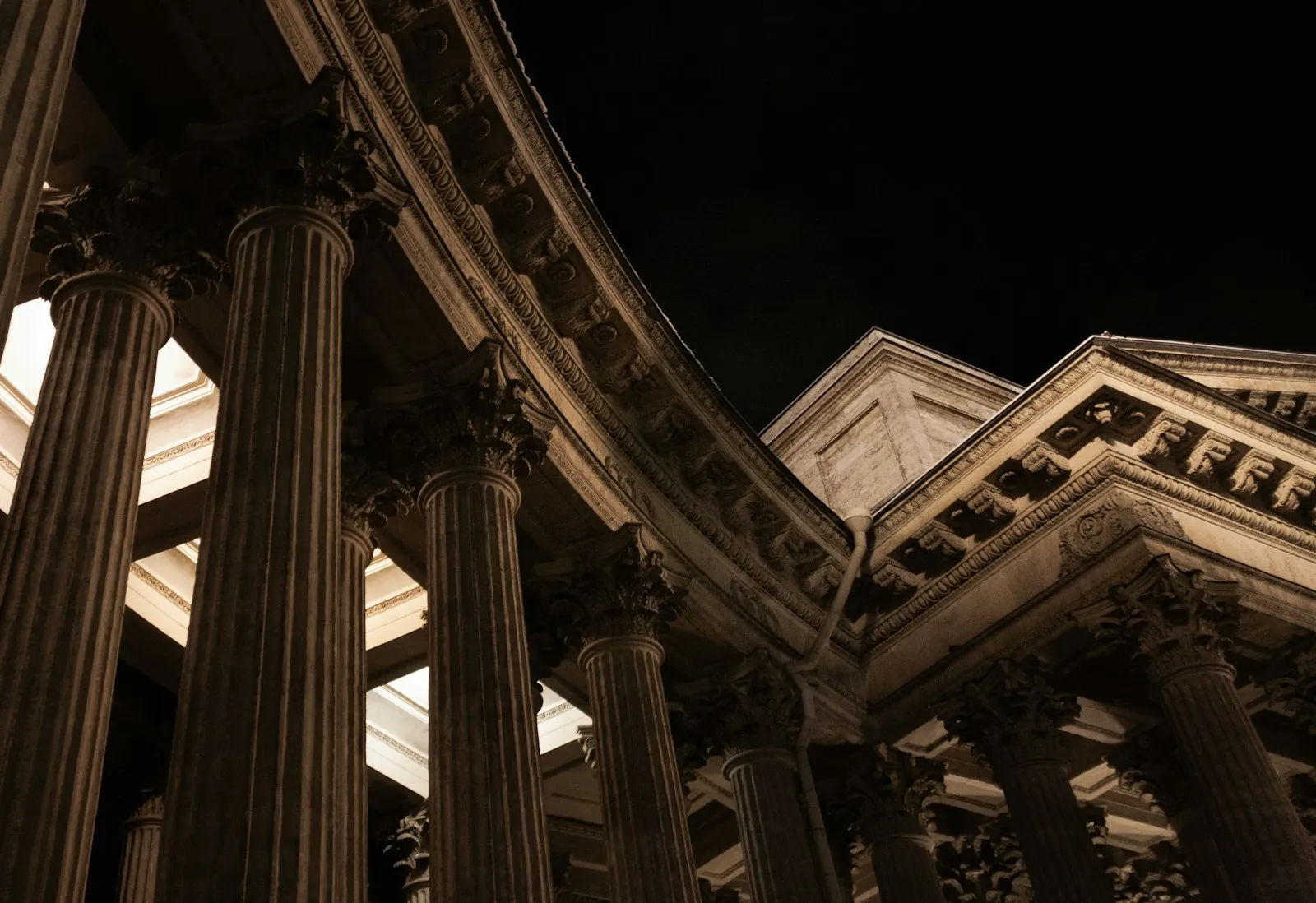 Colonnes classiques et corniches sculptées d'un édifice, vues en contre-plongée de nuit.